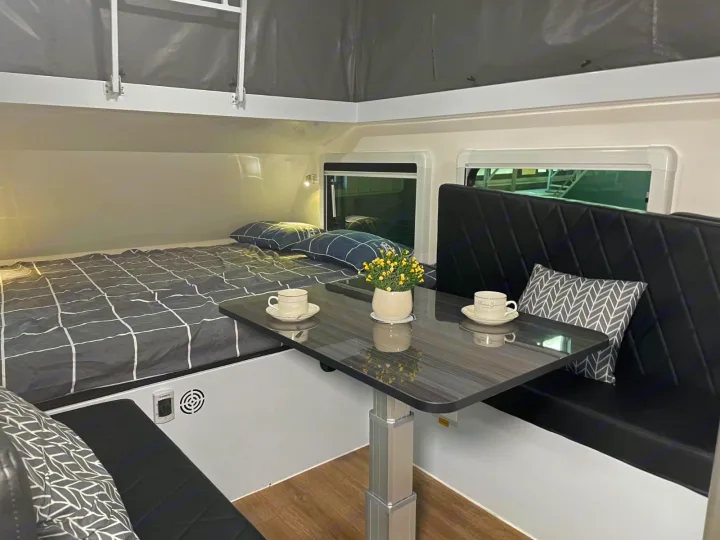 RV rental interior with a comfy bed, dining table set for two, and upholstered seating, ideal for your next road trip.. Zoomies Campers Eagle’s Nest 2025
