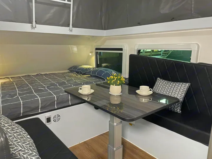 An RV rental interior with a comfy bed, adjustable dining table, and bench seating, set for travel.. Zoomies Campers Eagle’s Nest 2025
