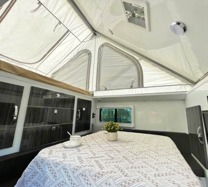 Cozy pop-up RV rental interior: dining area with table, seating, and a comfortable bed. Perfect for camping!. Zoomies Campers Spirit 2025