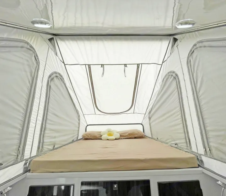 Cozy interior of a rooftop tent with a comfy bed, perfect for your RV rental adventure. Lights & windows visible.. Zoomies Campers Spirit 2025