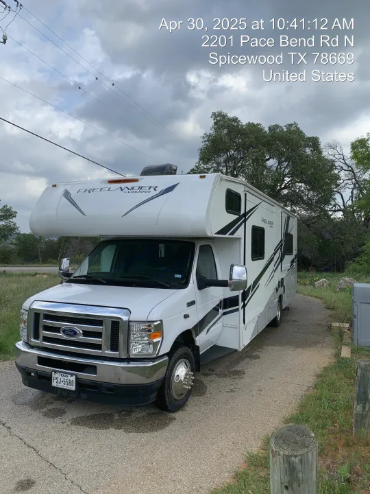 A white Coachmen Freelander RV rental motorhome is parked at 2201 Pace Bend Rd N, Spicewood, TX, under a cloudy sky.. Coachmen Freelander 2021