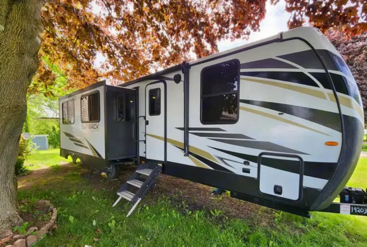 Spacious Outback RV rental travel trailer, white with bold graphics, steps deployed, and slide-out extended. Ready for adventure!. Keystone RV Outback 2021