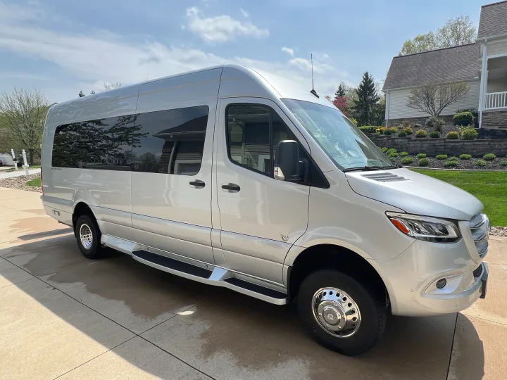 A silver Mercedes-Benz Sprinter van, ideal for rv rental adventures. This luxury conversion van is parked on a sunny driveway.. Ultimate Toys Ultimate Coach 2024