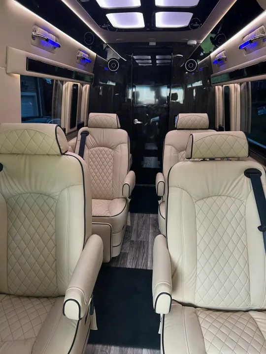 Spacious luxury RV rental interior with cream quilted leather seats, entertainment system, and accent lighting.. Ultimate Toys Ultimate Coach 2024