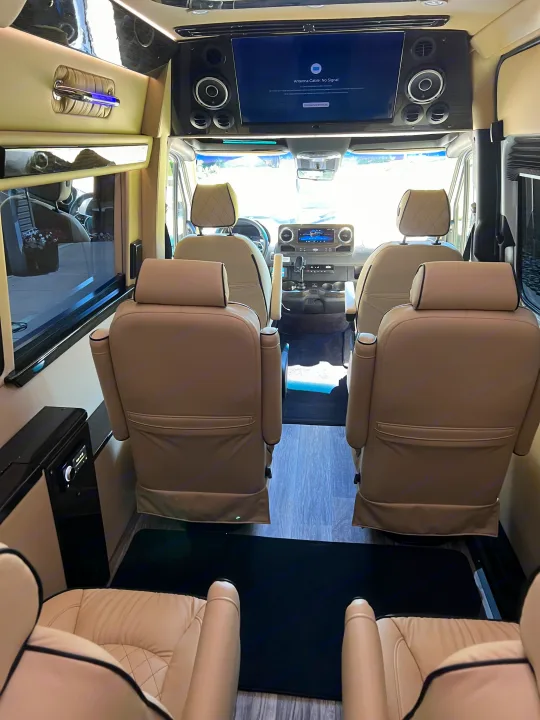 Luxury RV rental interior: tan leather captain's chairs, large screen, plush comfort for travel.. Ultimate Toys Ultimate Coach 2024
