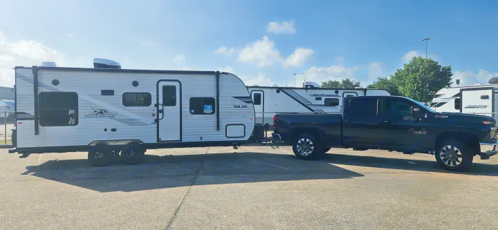 A black pickup truck is hitched to a white Jay Flight SLX travel trailer, showcasing an rv rental setup.. Jayco Jay Flight SLX 210 QB 2025