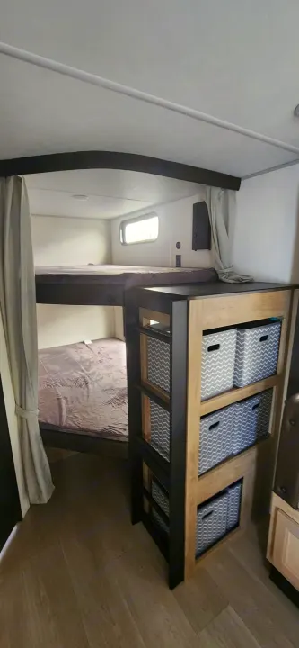 RV rental interior with bunk beds, privacy curtains, and a practical storage unit with patterned bins.. Forest River Cherokee Grey Wolf 2026