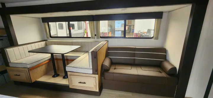 Explore this rv rental's interior: an L-shaped dinette with table & benches, plus a comfortable sofa, framed by large windows.. Forest River Cherokee Grey Wolf 2026