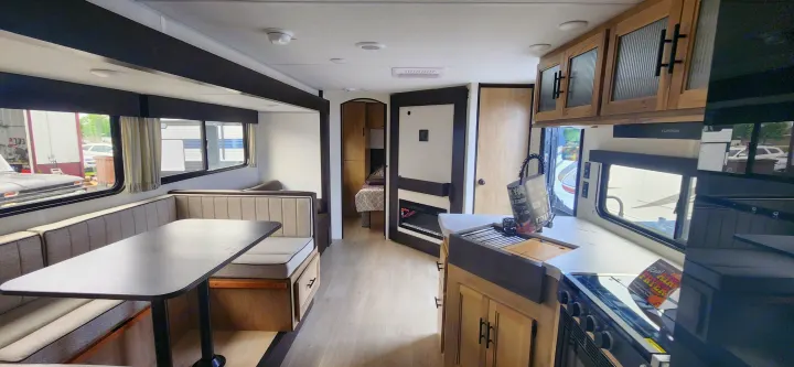 Explore this clean RV rental interior, featuring a cozy dining booth, full kitchen, electric fireplace, and private sleeping area.. Forest River Cherokee Grey Wolf 2026