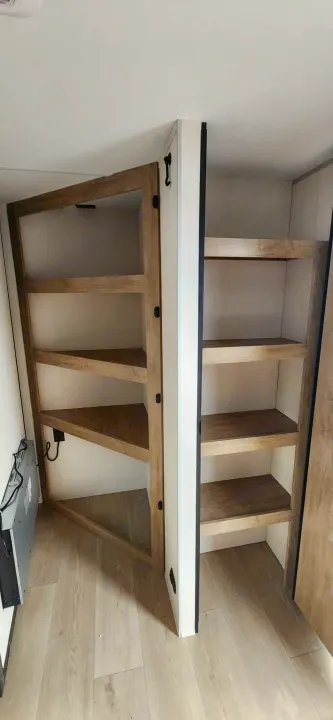RV rental kitchen area showing a clever swing-out pantry with triangular shelves & adjacent storage.. Forest River Cherokee Grey Wolf 2026