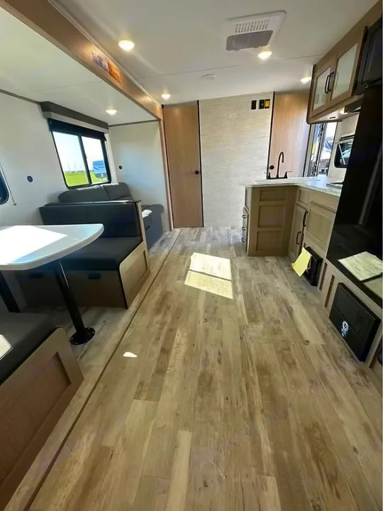 Spacious RV rental interior featuring a modern kitchen, comfortable dining area, and light wood-look flooring.. Gulf Stream Amerilite 2025