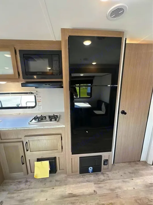 Inside this RV rental: modern kitchen with microwave, 2-burner stovetop, large refrigerator, and cabinets.. Gulf Stream Amerilite 2025