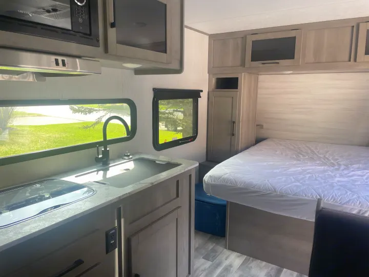 Explore this RV rental's inviting interior: featuring a compact kitchen with sink, microwave, and a comfortable bed.. Dutchmen Kodiak Cub 2021