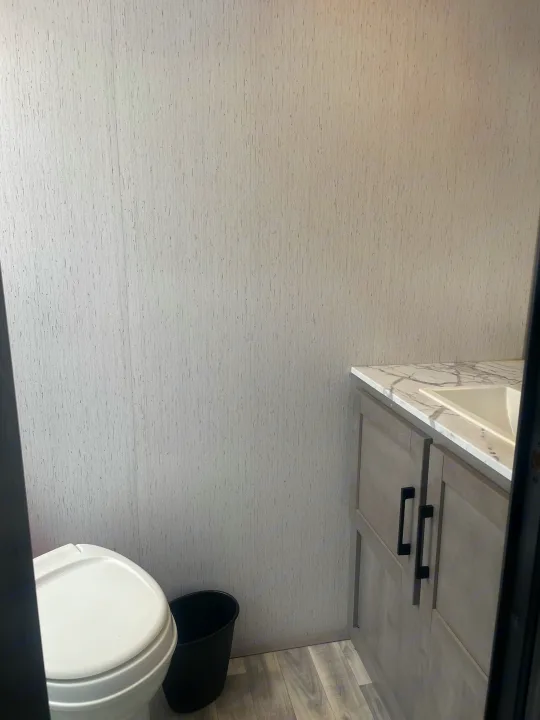 RV rental bathroom features a compact toilet, vanity with sink, and light, textured walls. Functional design for travel.. Dutchmen Kodiak Cub 2021