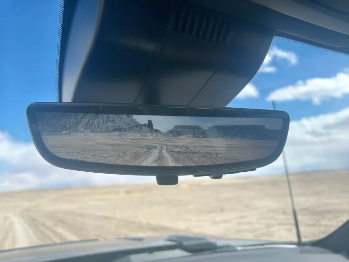 Inside an RV rental, a digital rearview mirror shows a desert path leading to distant mesas. Blue sky and vast terrain outside.. Chevrolet Silverado 2500HD ZR2 Bison 2025