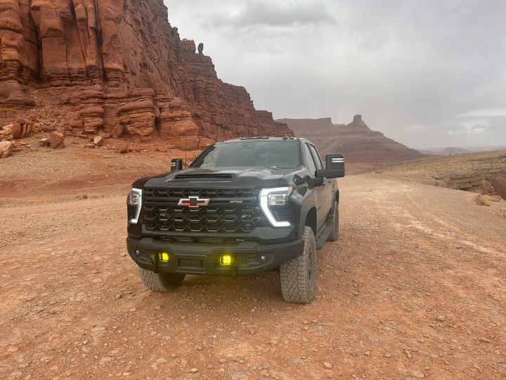A black Chevy truck on a red desert road, towering cliffs behind. Perfect for your off-road adventure or an RV rental trip!. Chevrolet Silverado 2500HD ZR2 Bison 2025