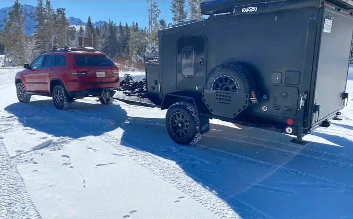 RV rental: Red SUV tows an off-road camper through snowy mountains. Ready for winter camping adventures.. ITWO custom Pixtech Bearlander 20 2024