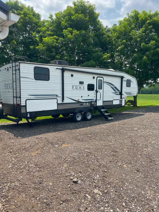 Spacious Puma travel trailer RV rental parked on a gravel lot, ready for your next outdoor adventure.. Forest River Palomino Puma 2022
