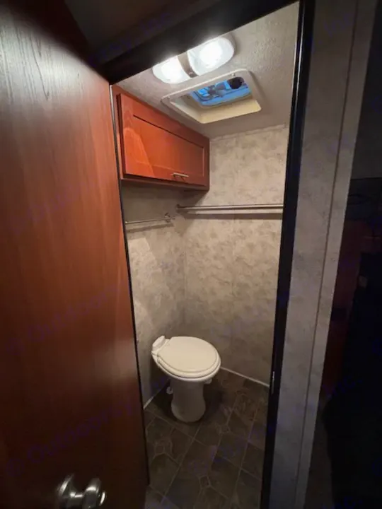 Step into this RV rental's compact bathroom, featuring a toilet, overhead cabinet, vent, and handy hanging rod.. Keystone RV Fuzion Toy Hauler 2009