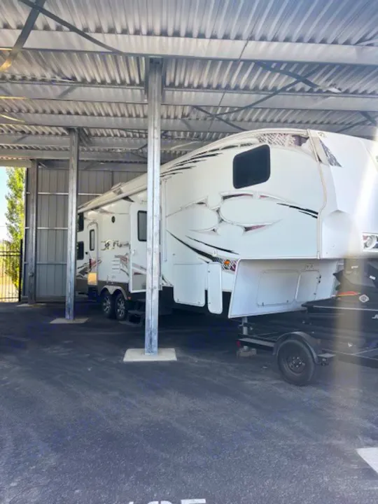 Spacious covered storage for a large white fifth-wheel RV. Great option for RV rental needs.. Keystone RV Fuzion Toy Hauler 2009