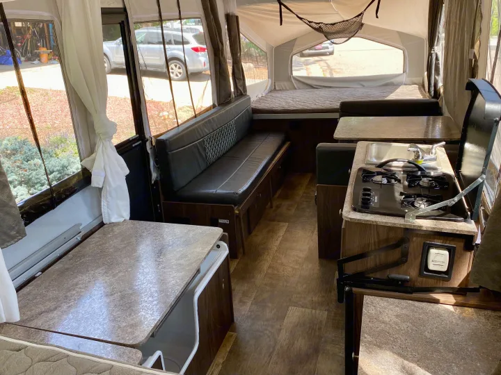 Experience comfort in this RV rental! Interior view of a pop-up camper with beds, dining, and kitchen amenities.. Forest River Rockwood ESP 2018