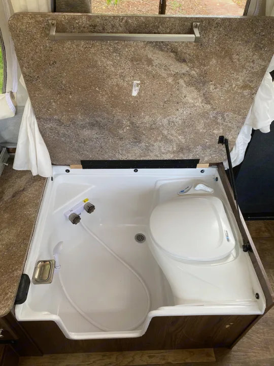Compact rv rental bathroom with shower and toilet, featuring a clever pop-up design for space efficiency.. Forest River Rockwood ESP 2018