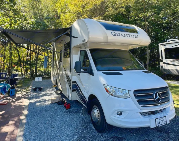 White Thor Quantum rv rental, a Mercedes-Benz motorhome, parked at a sunny campsite with its awning extended.. Thor Quantum 2022