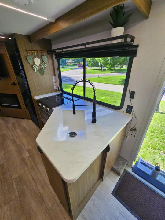 Spacious RV rental kitchen with sink, stove, and a bright window view. Perfect for your next adventure!. Forest River 26Ice 2025
