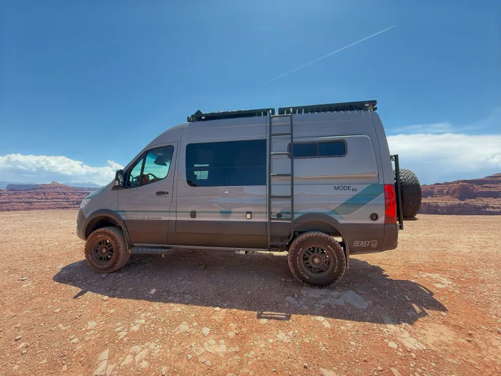 Gray Storyteller Overland camper van for rv rental, parked on red earth with distant desert mountains, ideal for adventure travel.. Storyteller Overland Storyteller Overland Class B 2023