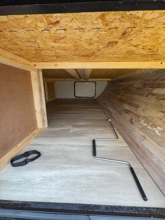 RV rental's pass-through storage area: OSB ceiling, wood frame, tiled laminate floor, rear access hatch, crank, and strap.. Gulf Stream Coach Enlighten 17bh 2025