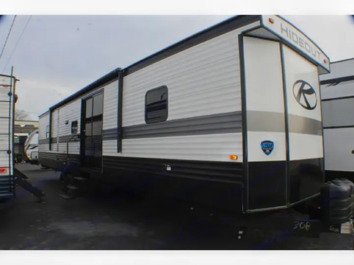This large white, black, and grey Hideout travel trailer is parked outdoors, great for an RV rental.. evergreen sun valley 2015