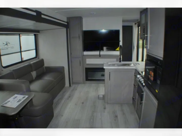 Modern RV rental interior: grey kitchen, comfortable sofa, entertainment center with TV, and fireplace. Spacious for travel.. evergreen sun valley 2015