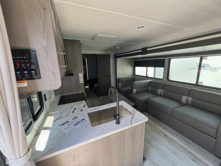 Spacious RV rental interior featuring a modern kitchen with a sink, and a comfortable living area with an L-shaped gray sofa.. evergreen sun valley 2015