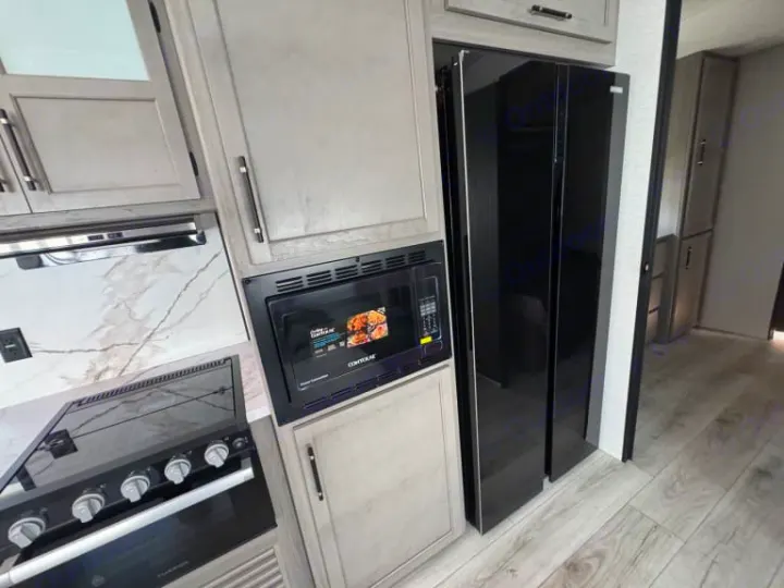 Experience a sleek RV rental kitchen. This modern galley features a black fridge, microwave, stovetop, and light wood-look cabinetry.. evergreen sun valley 2015