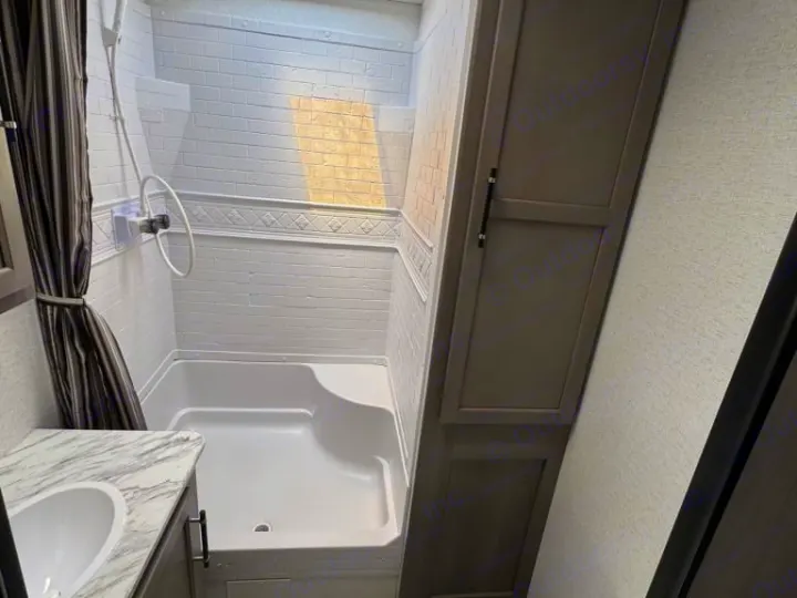 RV rental bathroom features white tiled shower, compact sink, and storage cabinet for comfortable travel.. evergreen sun valley 2015