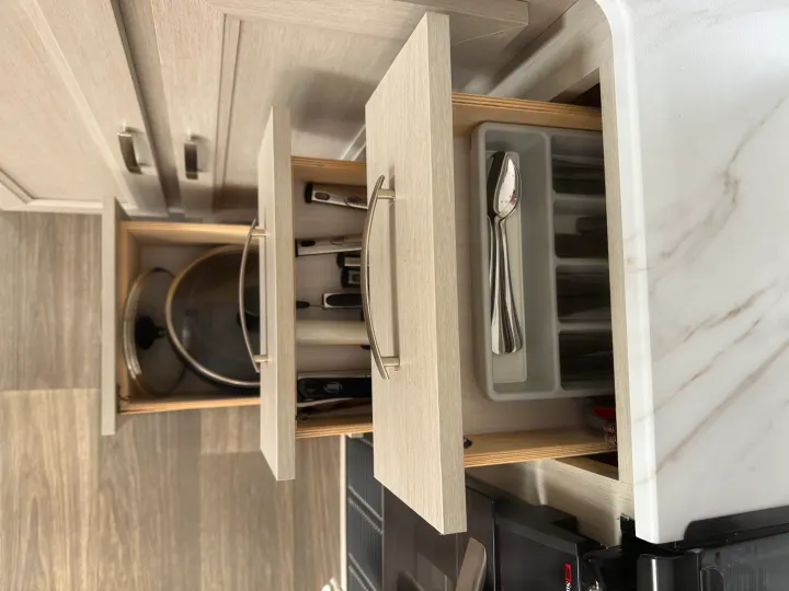 Organized RV rental kitchen with light-colored open drawers revealing cookware, various utensils, and silverware.. Cruiser RV Shadow Cruiser 2025