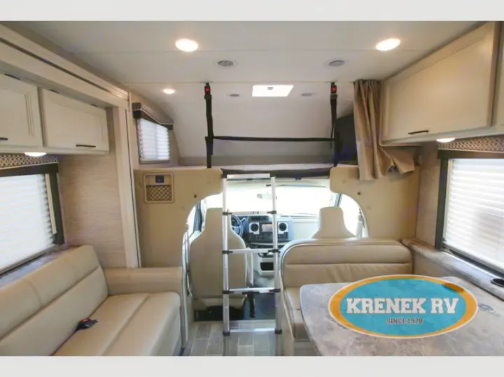 Spacious RV rental interior featuring a sofa, dining table, and bunk bed above the driver's cab.. Thor Chateau 2022