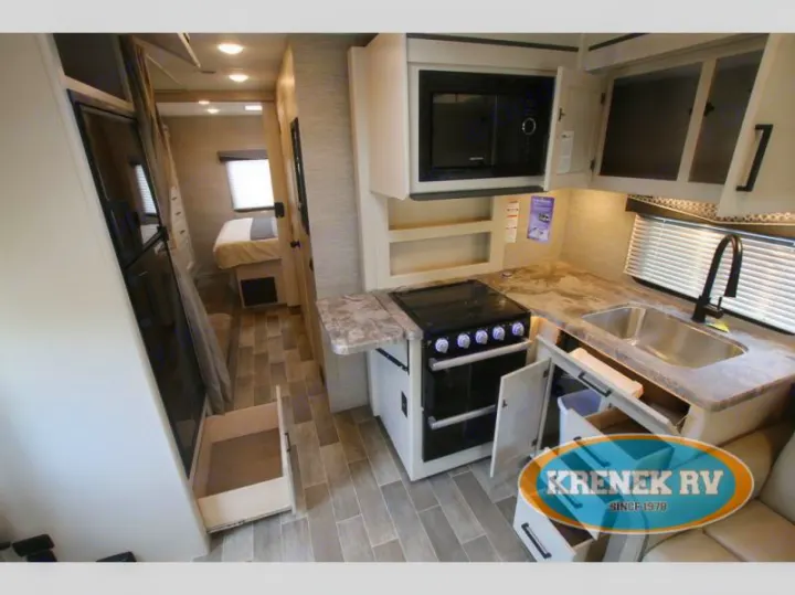 Explore this RV rental's modern interior. Features kitchen with stove, microwave, sink, and open storage. Bedroom visible.. Thor Chateau 2022