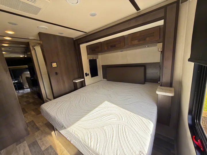 Clean RV rental shower with curved glass door, black fixtures, and skylight. Ready for refreshing stops on your journey.. FR3 FR3 Motorhome 2023