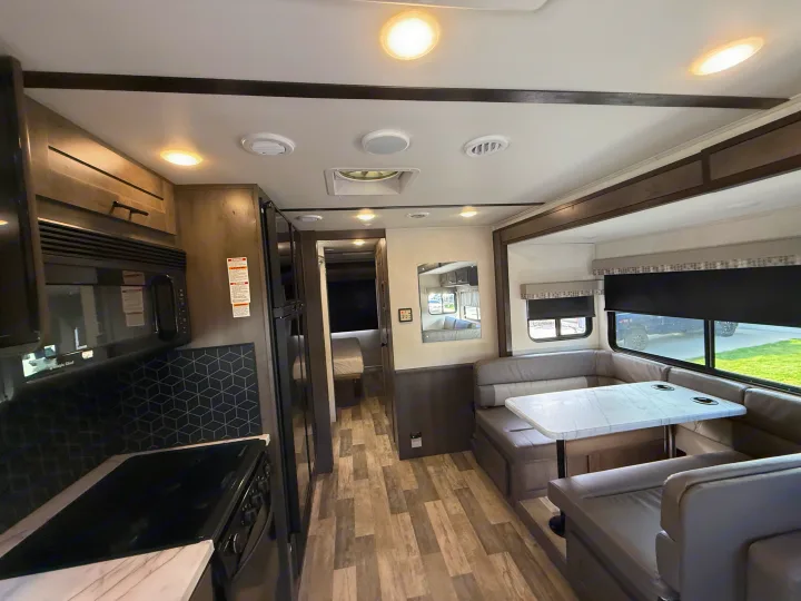 Bright RV rental interior with a modern kitchen, comfortable U-shaped dinette, and rear bedroom area.. FR3 FR3 Motorhome 2023