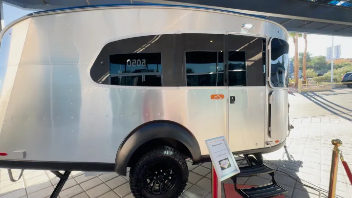 Sleek silver Airstream BasecampX travel trailer, ideal for an RV rental, showcased outdoors with rugged tires and large tinted windows.. Airstream Basecamp 2024