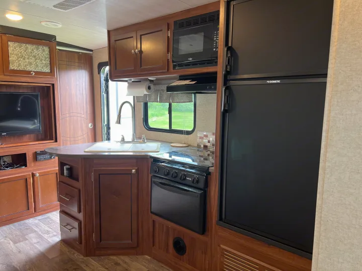 Spacious rv rental interior featuring a full kitchen with sink, stove, oven, microwave, refrigerator, and entertainment center.. Heartland RVs Mallard 2018