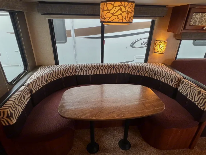 Comfortable RV rental dinette area with U-shaped seating, patterned cushions, and a central table.. Heartland RVs Mallard 2018