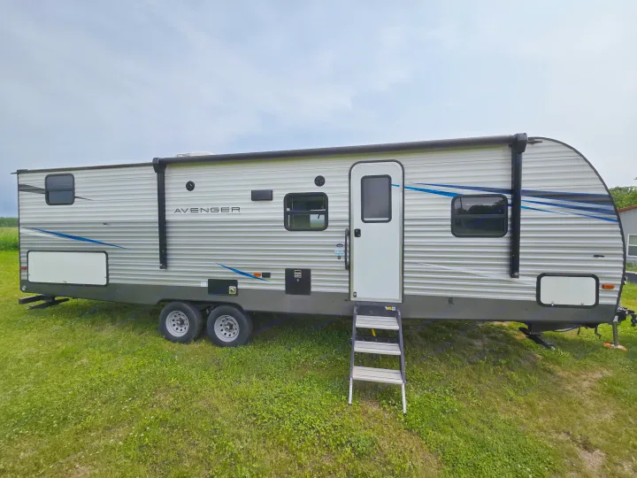 An Avenger travel trailer for RV rental, parked on grass under a cloudy sky, ready for adventure.. Avenger Avenger Trailer 2021