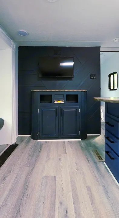 Modern RV rental living space featuring a dark accent wall, TV, media cabinet with stereo, and light wood flooring.. Crossroads RV Z-1 2015