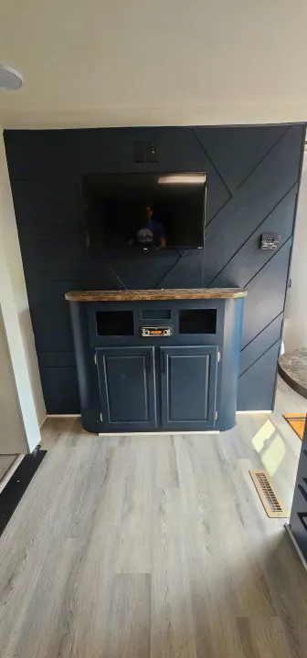 Stylish RV rental interior featuring a dark blue geometric accent wall with TV, media console, and light wood flooring.. Crossroads RV Z-1 2015