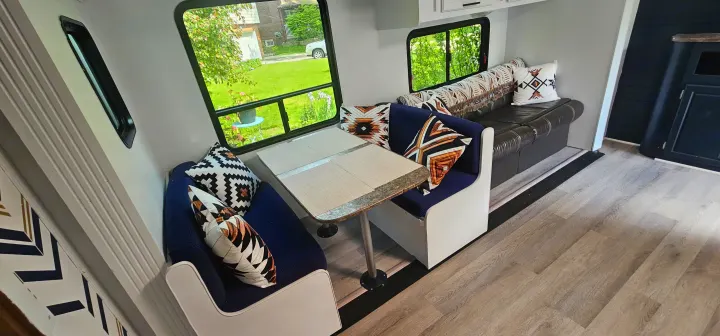 RV rental interior: cozy dinette & sofa with patterned pillows, bright windows, and wood-look floor.. Crossroads RV Z-1 2015