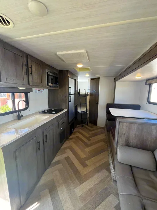 Spacious rv rental interior featuring a modern kitchen, cozy dinette, and bunk beds, perfect for family adventures on the road.. Forest River EVO 2021