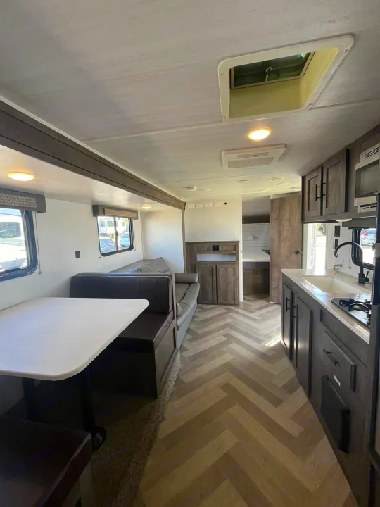 Spacious RV rental interior with modern kitchen, dinette, and living area, featuring herringbone floors.. Forest River EVO 2021