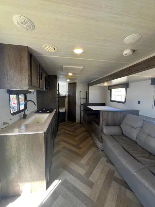 Modern RV rental interior with kitchen, dinette, sofa, and bunk beds. Ideal for family adventures.. Forest River EVO 2021